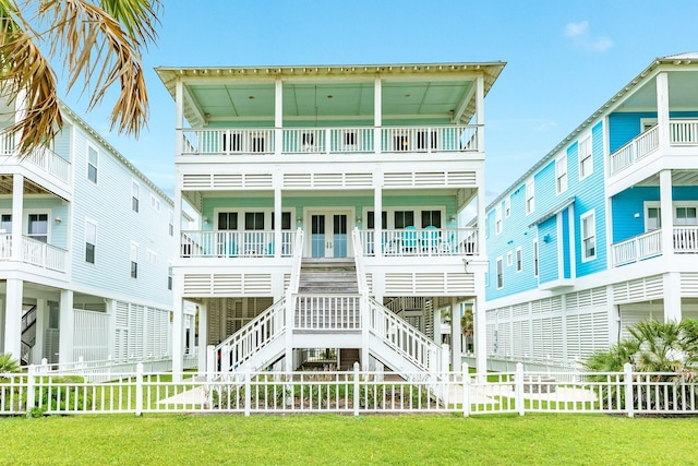 rear view of house with a lawn, french doors, a fenced backyard, and a balcony