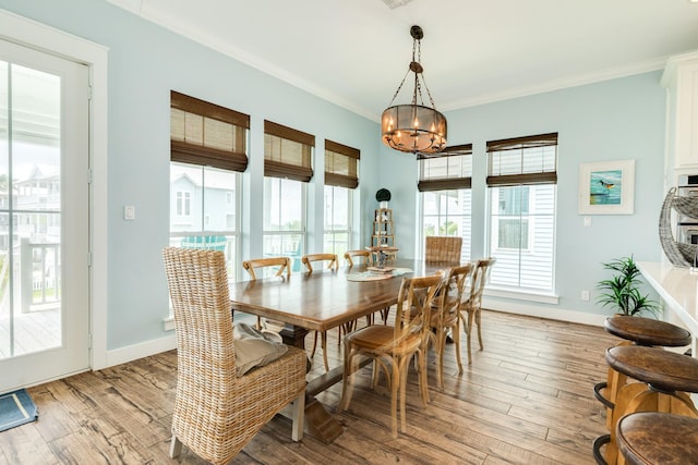 dining area with crown molding, light wood-style floors, and an inviting chandelier
