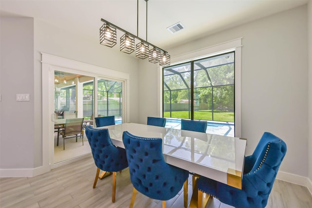 dining room with a healthy amount of sunlight, baseboards, light wood finished floors, and visible vents