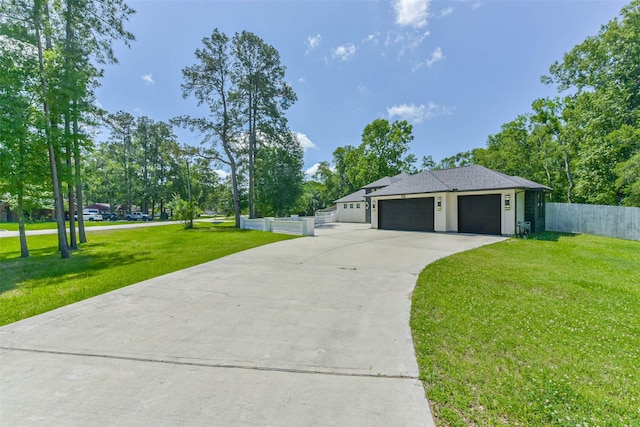 view of front of property featuring an attached garage, fence, driveway, and a front yard