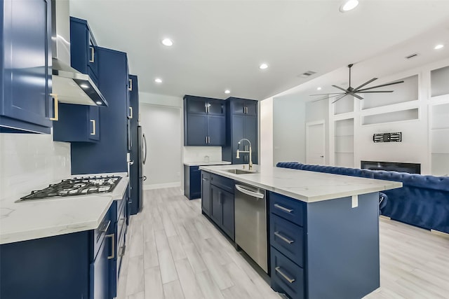 kitchen with a ceiling fan, blue cabinetry, appliances with stainless steel finishes, tasteful backsplash, and light wood-type flooring