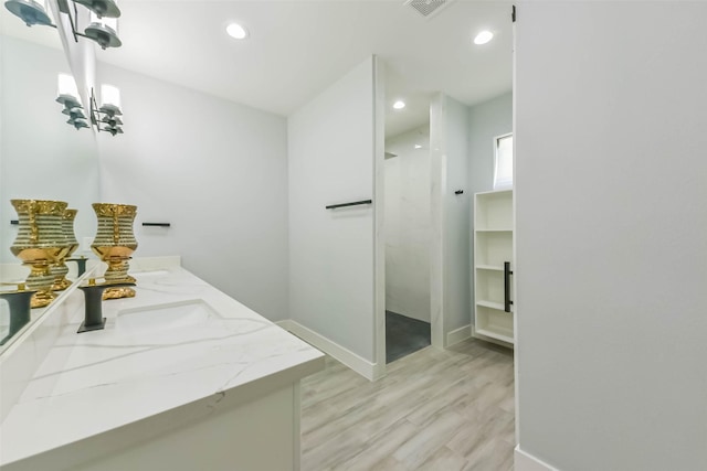 full bathroom featuring vanity, wood finished floors, baseboards, recessed lighting, and a walk in shower