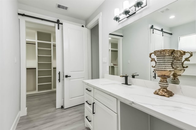bathroom featuring visible vents, wood finished floors, a spacious closet, and vanity