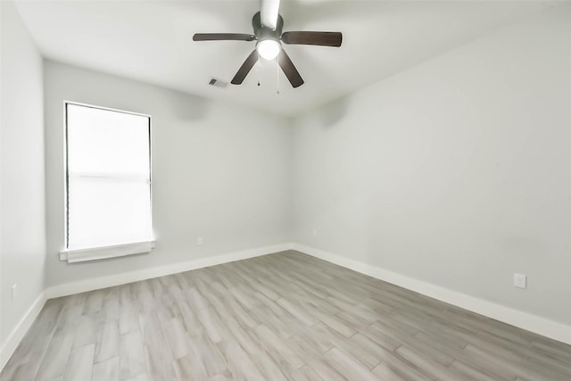 empty room with a ceiling fan, baseboards, visible vents, and wood finished floors
