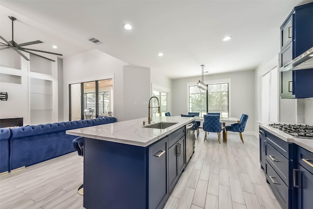 kitchen with visible vents, a kitchen island with sink, open floor plan, a sink, and stainless steel appliances