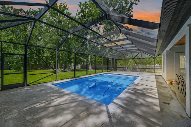 pool at dusk with a lawn, a fenced backyard, an outdoor pool, and a patio