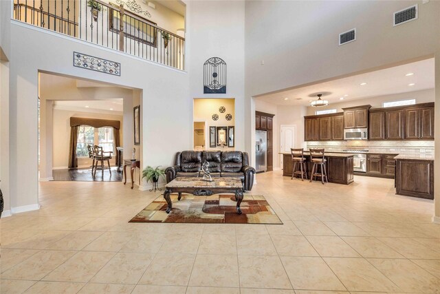 28202 Rippling Brook Ln, Fulshear, TX 77441 - living area featuring light tile patterned floors, baseboards, visible vents, and a towering ceiling