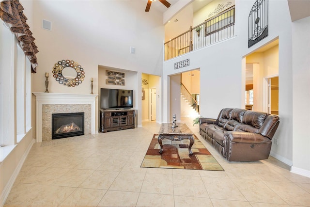 28202 Rippling Brook Ln, Fulshear, TX 77441 - living area featuring a tile fireplace, stairs, a ceiling fan, a towering ceiling, and visible vents