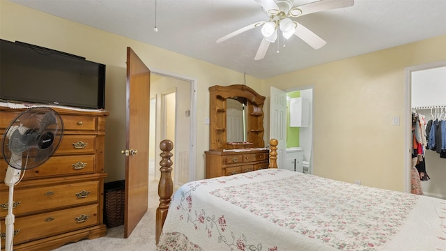 carpeted bedroom featuring a walk in closet, ceiling fan, ensuite bathroom, and a closet