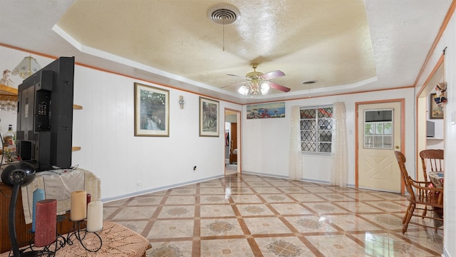 empty room with visible vents, baseboards, ceiling fan, a textured ceiling, and a tray ceiling