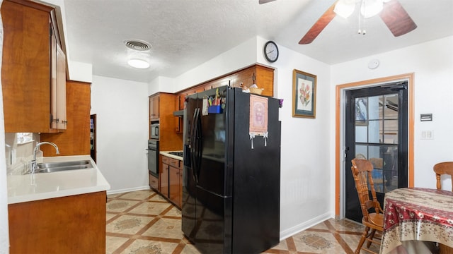 kitchen featuring visible vents, baseboards, brown cabinets, a sink, and black appliances