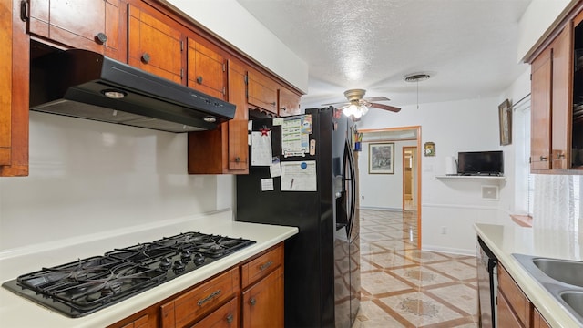 kitchen with black appliances, a ceiling fan, under cabinet range hood, and brown cabinetry