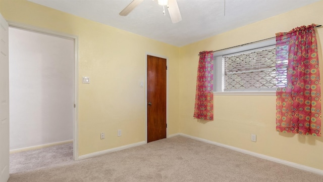 carpeted empty room featuring baseboards and a ceiling fan