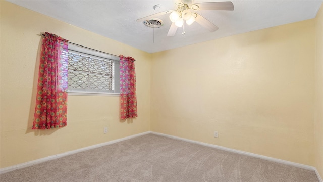 carpeted empty room with baseboards, a ceiling fan, and visible vents