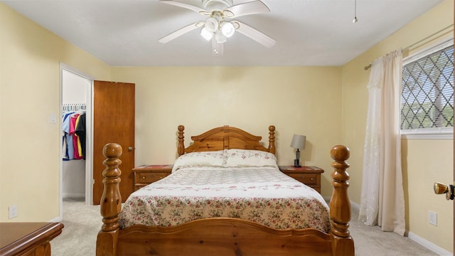bedroom featuring a walk in closet, a ceiling fan, light colored carpet, baseboards, and a closet
