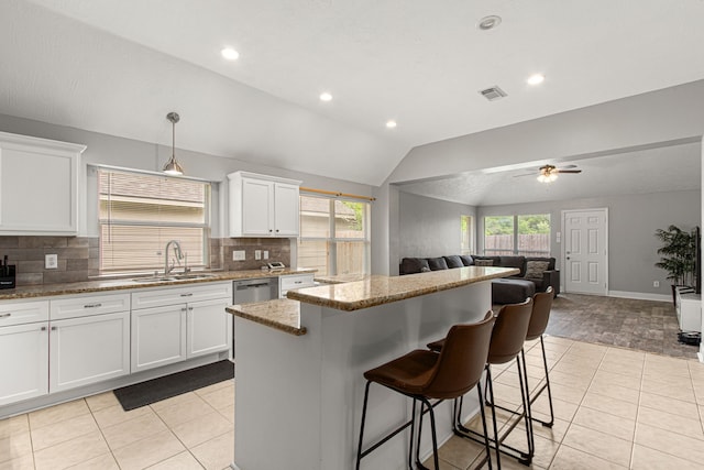 kitchen with a sink, open floor plan, vaulted ceiling, a kitchen island, and visible vents