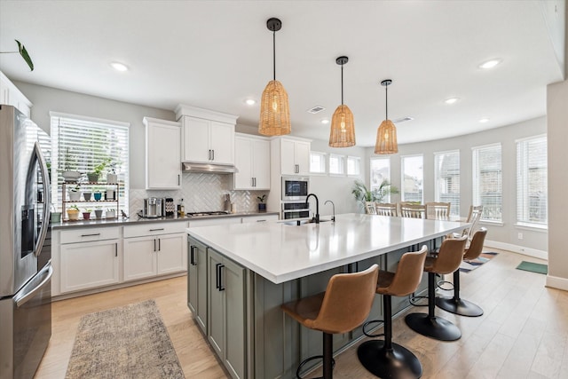 kitchen featuring backsplash, white cabinetry, appliances with stainless steel finishes, and a sink