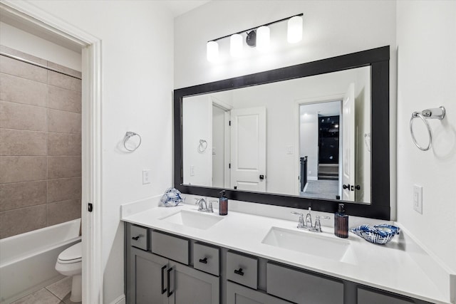 bathroom with double vanity, a sink, tile patterned floors, and toilet