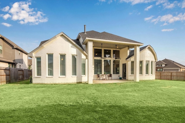 rear view of property with a lawn, a patio, brick siding, and a fenced backyard