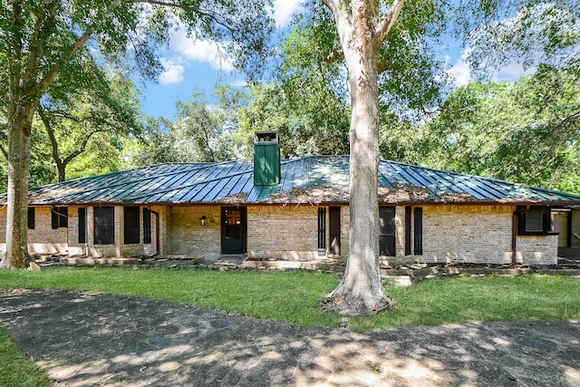 406 Hidden Creek Cir, Sealy, TX 77474 - mid-century inspired home featuring a standing seam roof, brick siding, a chimney, and a front yard