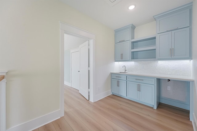 4042 Miramar Ct, Galveston, TX 77554 - kitchen with tasteful backsplash, open shelves, light countertops, a sink, and light wood finished floors
