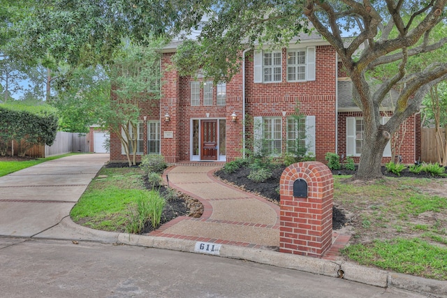 view of front facade featuring concrete driveway, brick siding, and fence