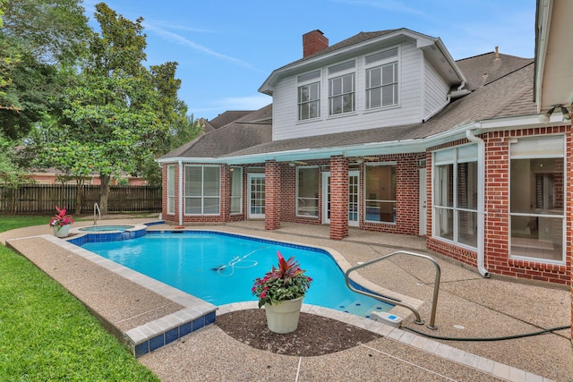 view of swimming pool with a pool with connected hot tub, fence, and a patio area
