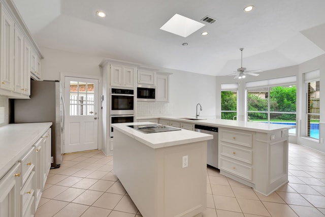 kitchen featuring visible vents, a peninsula, a center island, a sink, and stainless steel appliances