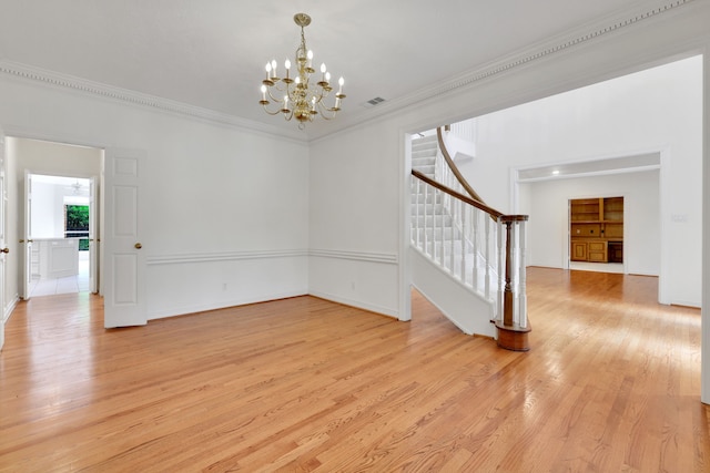 interior space featuring ornamental molding, stairs, light wood finished floors, and a notable chandelier