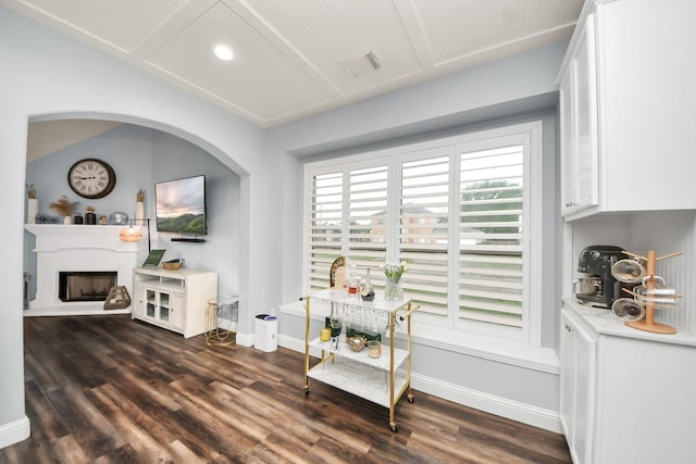 living area featuring visible vents, baseboards, a fireplace with raised hearth, dark wood-style floors, and recessed lighting
