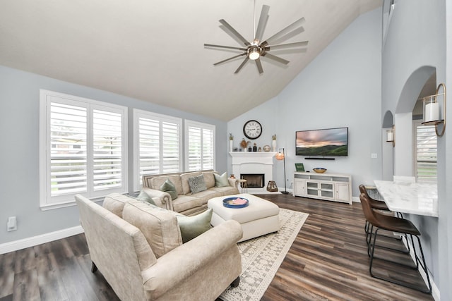 living area featuring a ceiling fan, high vaulted ceiling, a wealth of natural light, and arched walkways