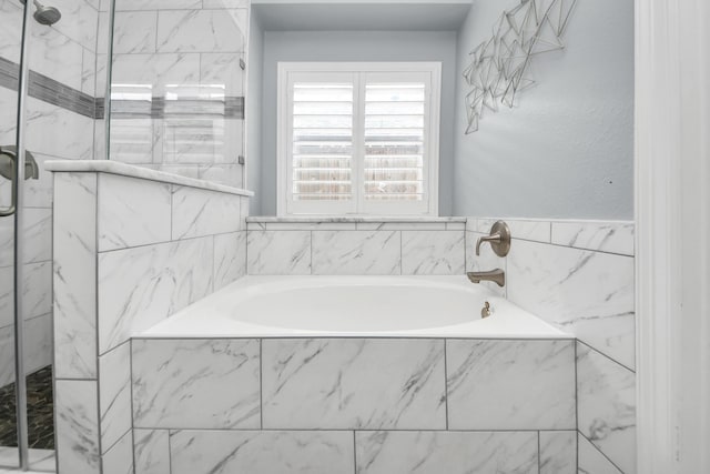 bathroom with a marble finish shower and a garden tub