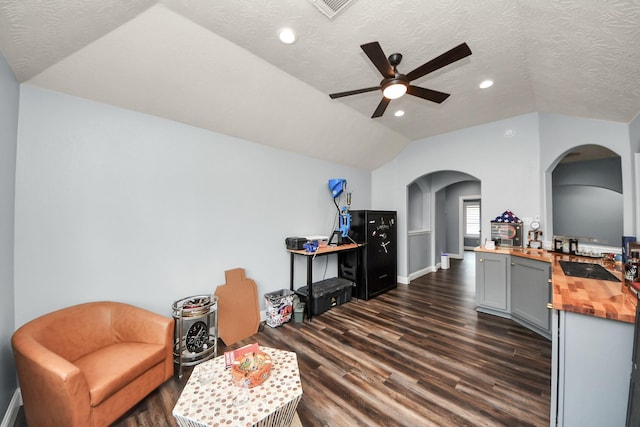 living area with arched walkways, ceiling fan, lofted ceiling, and dark wood-style floors