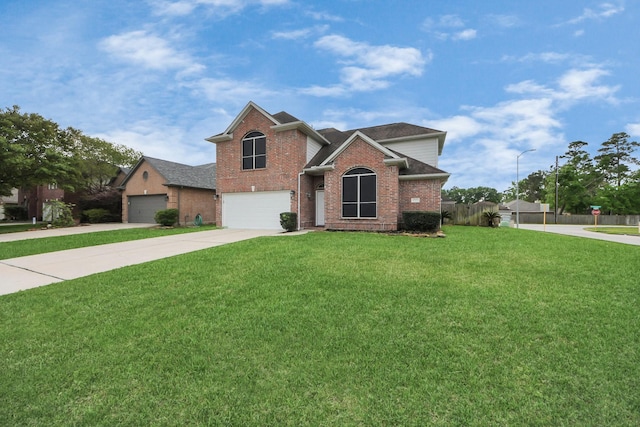 traditional-style home featuring fence, an attached garage, brick siding, a front yard, and concrete driveway