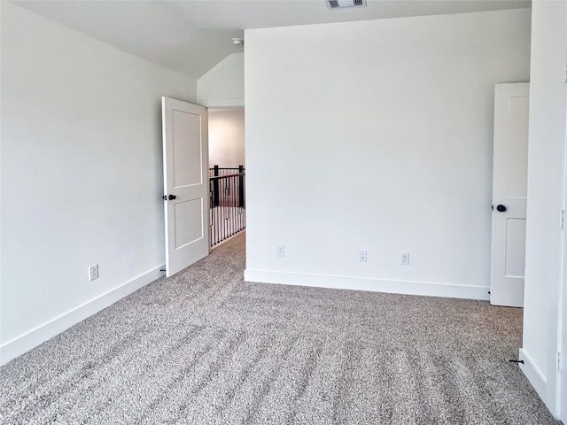 carpeted spare room featuring baseboards, vaulted ceiling, and visible vents