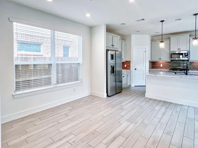 kitchen featuring light countertops, light wood finished floors, tasteful backsplash, and stainless steel appliances