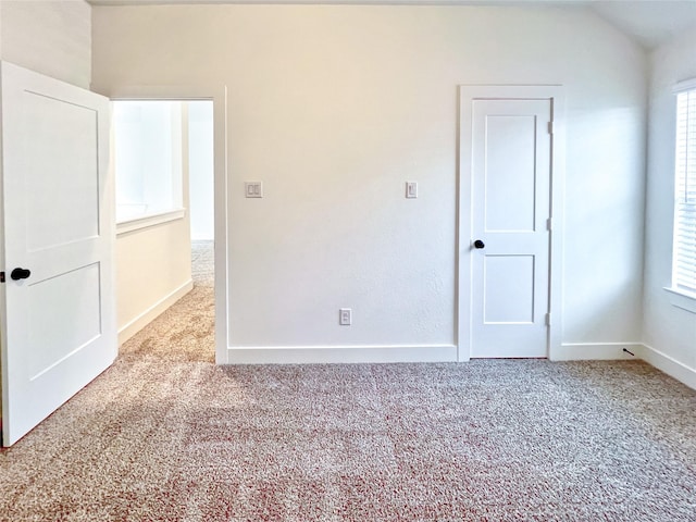 unfurnished room with carpet floors, baseboards, and lofted ceiling