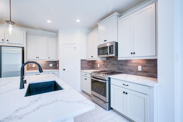 kitchen with decorative backsplash, decorative light fixtures, a sink, white cabinets, and stainless steel appliances