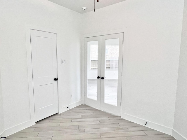 unfurnished room featuring light wood-style floors, baseboards, and french doors