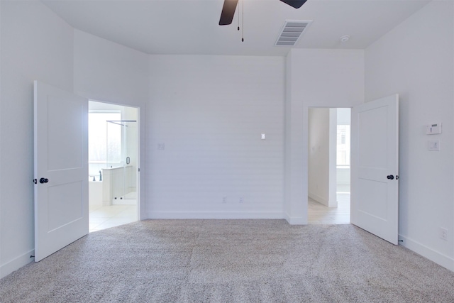 unfurnished room featuring baseboards, a ceiling fan, light colored carpet, and visible vents