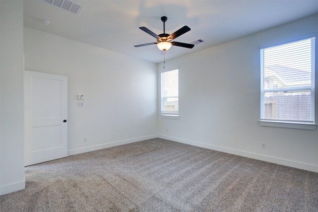 carpeted spare room with visible vents, a ceiling fan, and baseboards