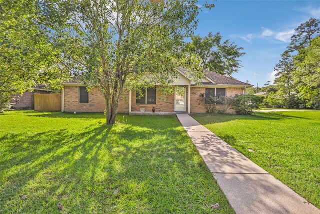 view of front of home featuring brick siding, fence, and a front yard