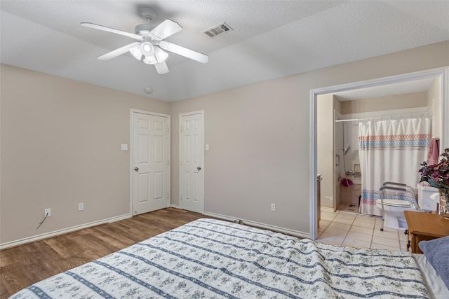 bedroom with light wood-style flooring, a ceiling fan, baseboards, ensuite bathroom, and visible vents