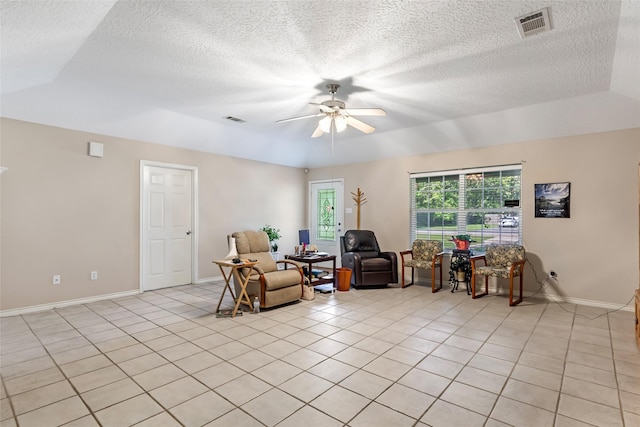 living area featuring visible vents, light tile patterned flooring, baseboards, ceiling fan, and a textured ceiling