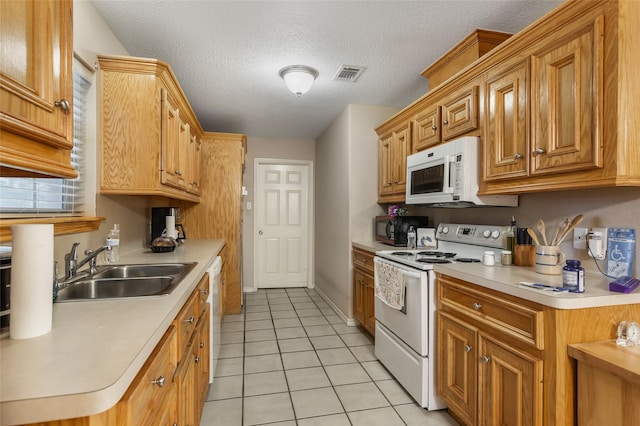 kitchen featuring visible vents, a sink, light countertops, light tile patterned floors, and white appliances