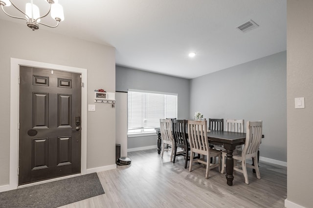 dining area with an inviting chandelier, light wood finished floors, baseboards, and visible vents