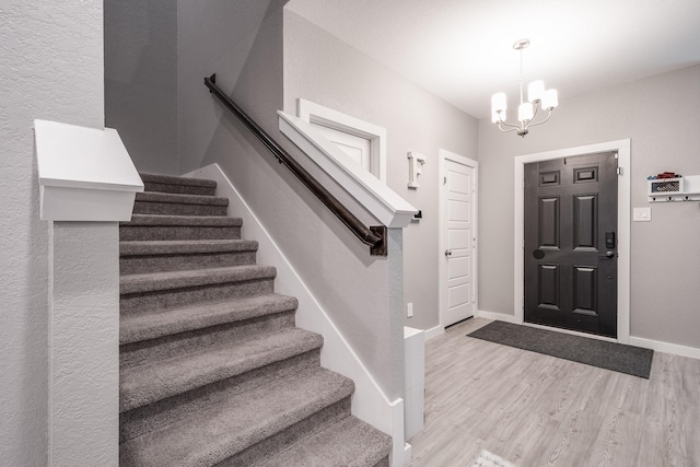 entryway featuring an inviting chandelier, baseboards, wood finished floors, and stairway