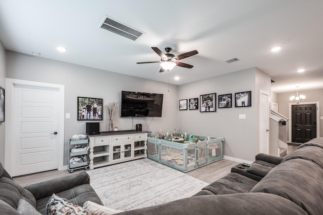 living room featuring baseboards, ceiling fan with notable chandelier, wood finished floors, and visible vents