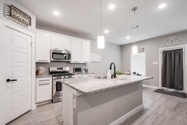 kitchen with stainless steel appliances, visible vents, a sink, and light wood-style flooring