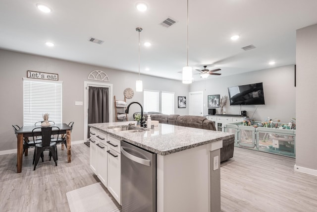 kitchen with visible vents, a center island with sink, a sink, and light wood-type flooring